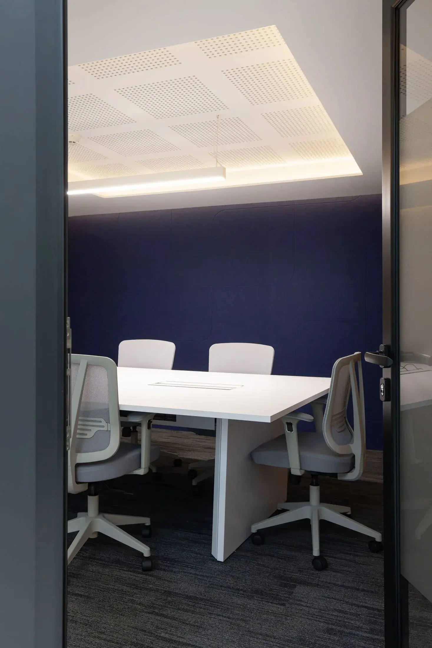 Sala de reuniones con puerta de vidrio y pared azul